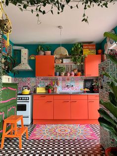 a kitchen with orange cabinets and black and white checkered flooring, potted plants on the wall