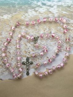 This pink womens rosary is very unique yet a very simple design. Each Our Father bead is decoratively wrapped with steel 22 gauge wire. The beads are made with Glass and Rondelle shaped which give a very unique design to the rosary. Each bead has a decorative rose flower embedded in the bead with a silver/gold decorative strip around it. The color is very light and elegant. This rosary would be the perfect gift a New Mother, Mother to be or any Mother as it has a centerpiece with Our Lady holdin Spiritual Wire Wrapped Rosary As Gift, Spiritual Gift Wire Wrapped Rosary, Rosary Jewelry, Mother To Be, Mother Mother, Holy Rosary, Catholic Rosary, Our Father, The Rosary