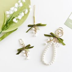 three pieces of jewelry sitting on top of a white table next to flowers and a plant