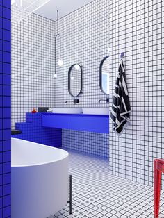 a white bath tub sitting next to a blue sink in a room with tiled walls