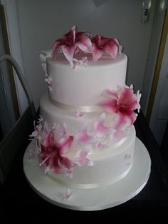 a three tiered white cake with pink flowers on it