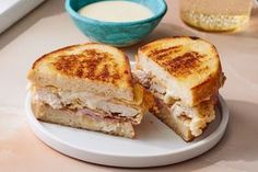 a sandwich cut in half sitting on top of a white plate next to a cup