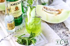 there are many bottles and glasses on the table with watermelon, mint, gin