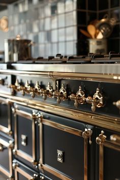 an old fashioned black and gold kitchen with lots of brass handles on the drawers,