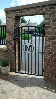 an iron gate with the letter m on it and a potted plant next to it