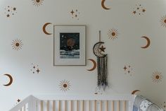 a baby's room with stars and moon decals on the wall, next to a crib