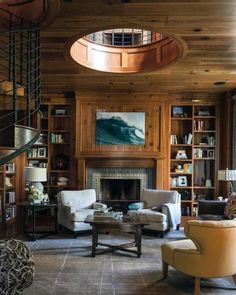 a living room filled with furniture and a fire place under a spiral stair case next to a book shelf