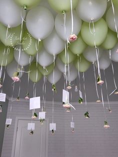 some balloons are hanging from the ceiling with white string and flowers on them as if to say congratulations