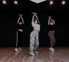 three young women are practicing yoga in an empty room with lights on the wall behind them