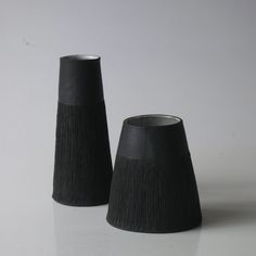 two black vases sitting next to each other on a table