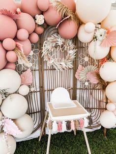 a chair sitting in front of a backdrop with balloons and flowers on the wall behind it