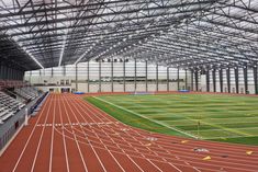 the inside of an indoor sports stadium with rows of empty seats and green grass on the ground