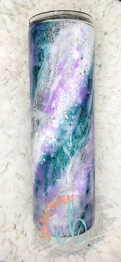 a purple, blue and white marbled tumbler sitting on a furry surface