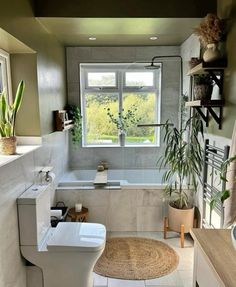 a bathroom with a toilet, sink and bathtub next to a window in it