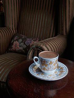 a cup and saucer sitting on top of a table next to a striped chair