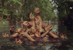 several people are floating in the water with their hands up and arms out to each other