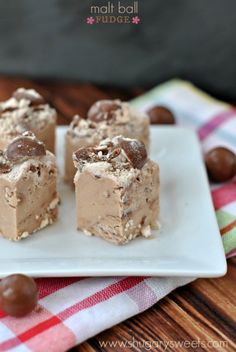 three pieces of ice cream dessert on a white plate with chocolate candies around it