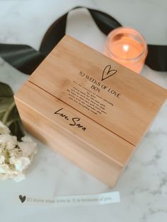 a personalized wooden box next to flowers and a candle