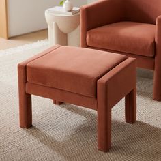 an orange chair and footstool sitting on a rug in front of a toilet