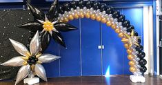 an arch made out of balloons with flowers and stars on the top is in front of a blue wall