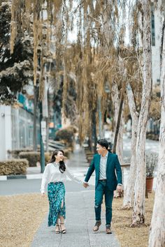 a man and woman walking down a sidewalk holding hands