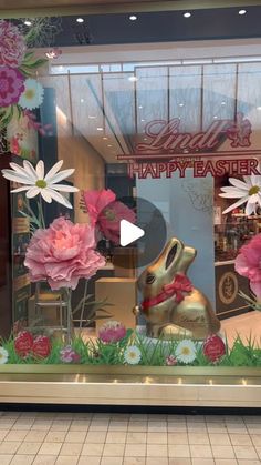 a window display with pink flowers and a gold rabbit