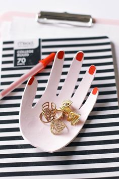 a pair of gold rings sitting on top of a white tray next to a red pen