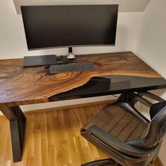 a computer desk with a monitor and keyboard on it in front of a wooden floor