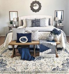 a bed with blue and white pillows on top of it next to a coffee table