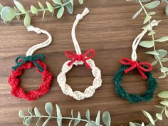 three bracelets made out of rope on top of a wooden table next to green leaves