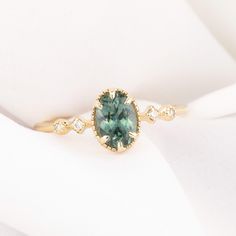 a close up of a ring with a green stone in it on a white cloth