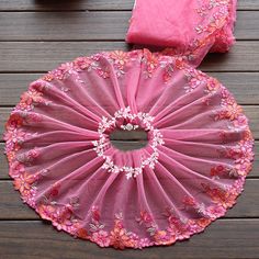 the pink flowered parasol is sitting on top of a wooden table next to two pillows