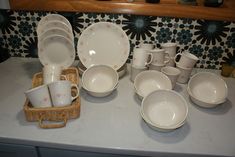 an assortment of white dishes and cups on a counter