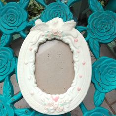 a white frame with pink flowers and hearts on it sitting on a blue tablecloth