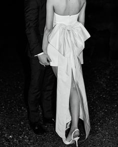 a man and woman standing next to each other in front of a dark background wearing formal attire