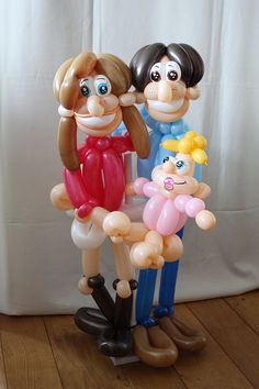 an inflatable balloon sculpture of two people and a child on a wooden floor