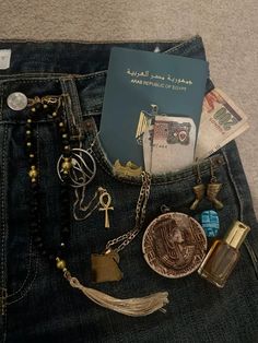 the contents of a purse are laid out on the back of a pair of jeans