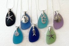 six different colored sea glass pendants hanging from strings with starfish and shells on them