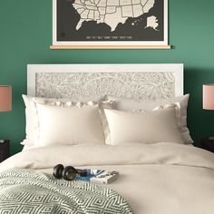 a bedroom with green walls, white bedding and a map on the wall above it