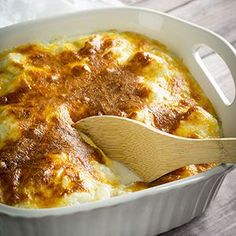 a casserole dish with meat and cheese in it is being stirred with a wooden spoon