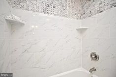 a white bath tub sitting next to a tiled wall