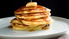 a stack of pancakes on a plate with syrup being drizzled over them