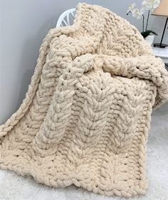 a blanket that is sitting on top of a chair next to a table with flowers