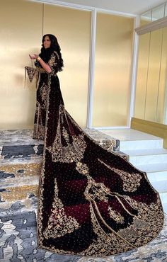 a woman in a black and gold wedding dress standing on some steps with her handbag