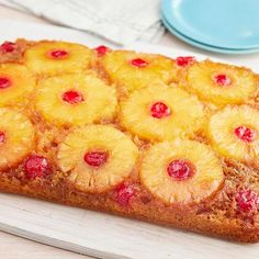 a pineapple upside down cake sitting on top of a cutting board next to a plate