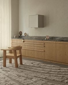 a wooden chair sitting on top of a rug in front of a kitchen countertop