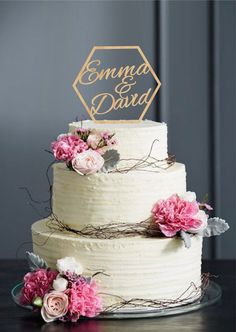 a wedding cake with pink flowers and mr and mrs signs on it's top