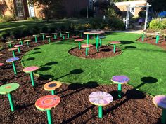 there are many small tables in the grass near each other on this lawn, and one is painted with different colors