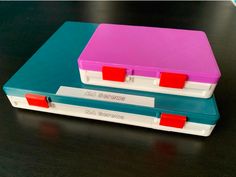 two plastic cases sitting side by side on a black table with red and blue handles