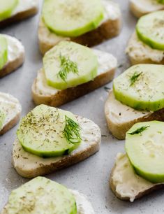 cucumber slices are arranged on top of bread with cream cheese and dill